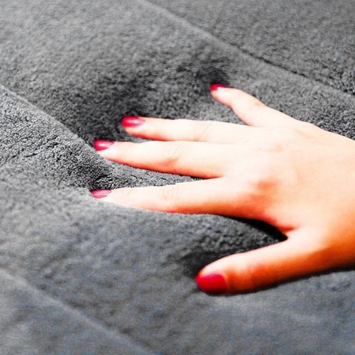 Hand with red nail polish on a textured gray surface