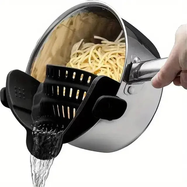 Pasta being drained with a black pasta strainer over a pot.