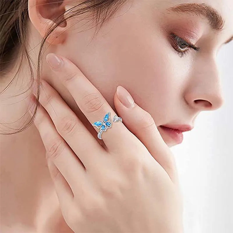 Close-up of a woman wearing a butterfly-themed ring on her finger.