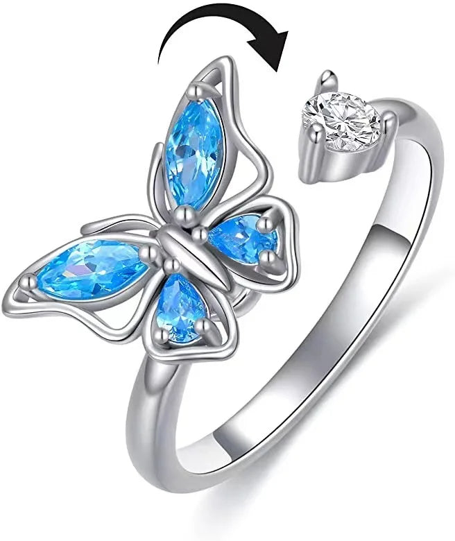 Butterfly-shaped ring with blue gemstones and a diamond on a white background