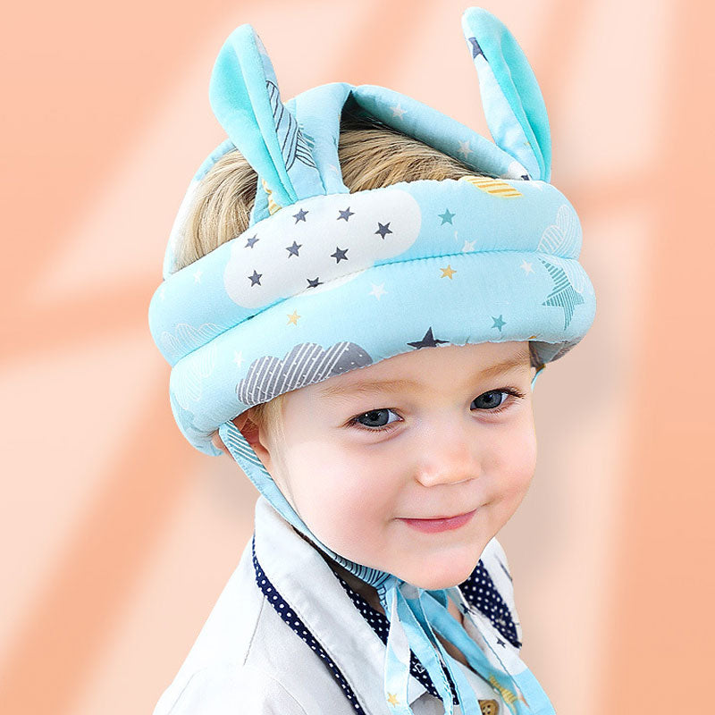 Child wearing a blue helmet with star pattern on a soft peach background