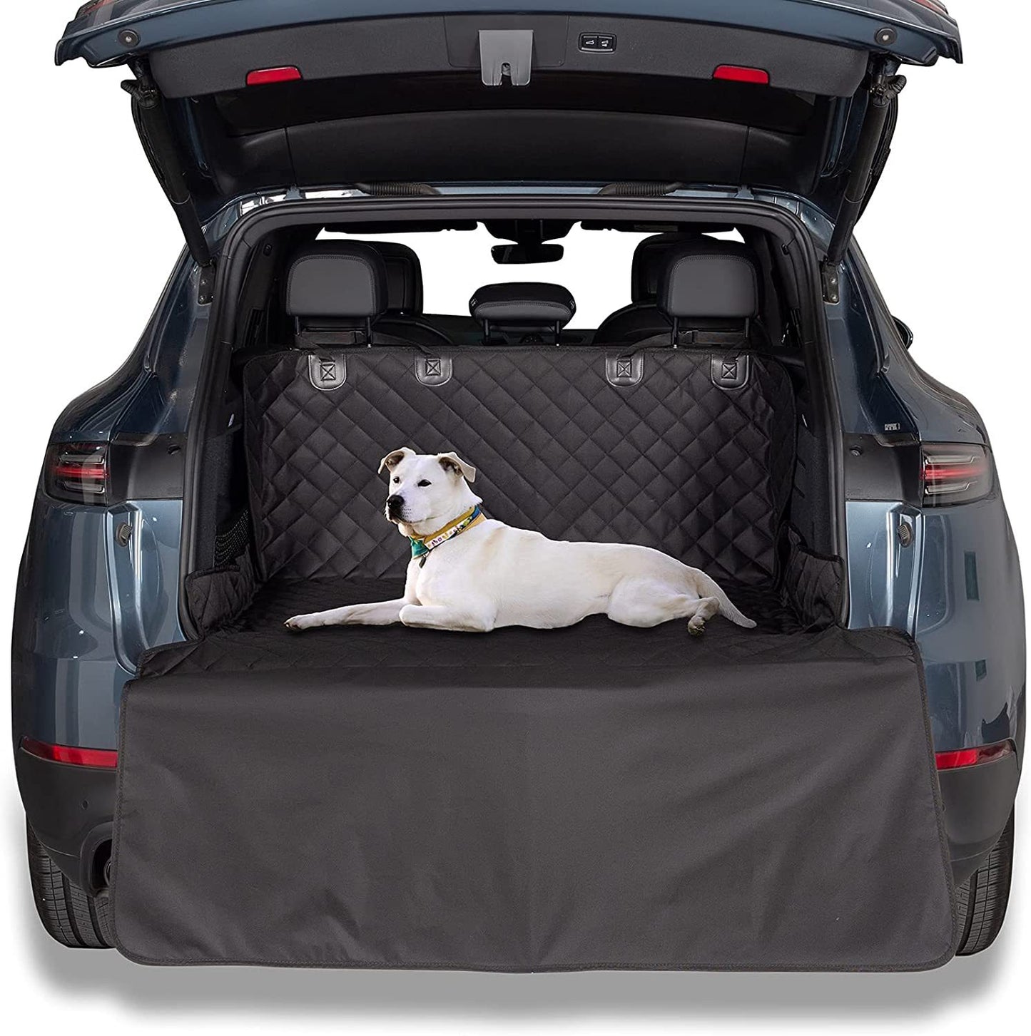 Dog lying on a black car trunk mat with a vehicle's open trunk in the background