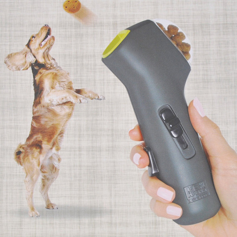 Hand holding a gray electronic pet treat launcher device with a dog on a checkered background
