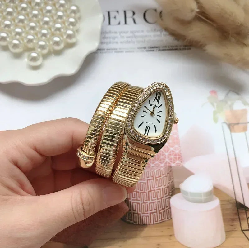 Gold bracelet watch held by a hand with a decorative background
