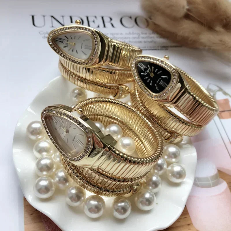 Gold wristwatch with decorative design on a white surface with pearls