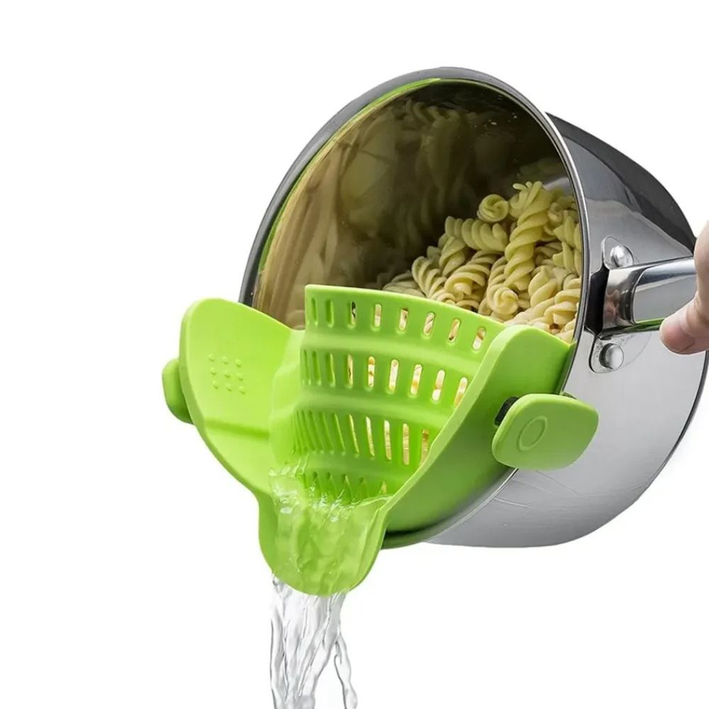 Green kitchen tool being used to drain pasta from a pot.