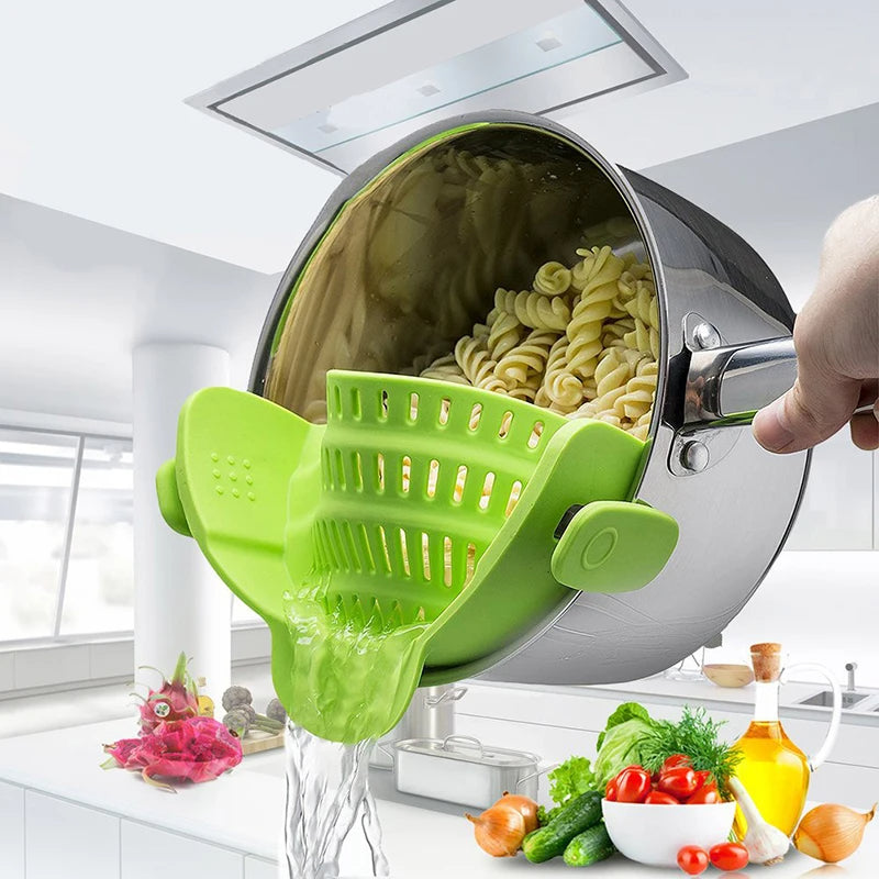 Green kitchen tool being used to drain pasta from a pot in a kitchen setting.