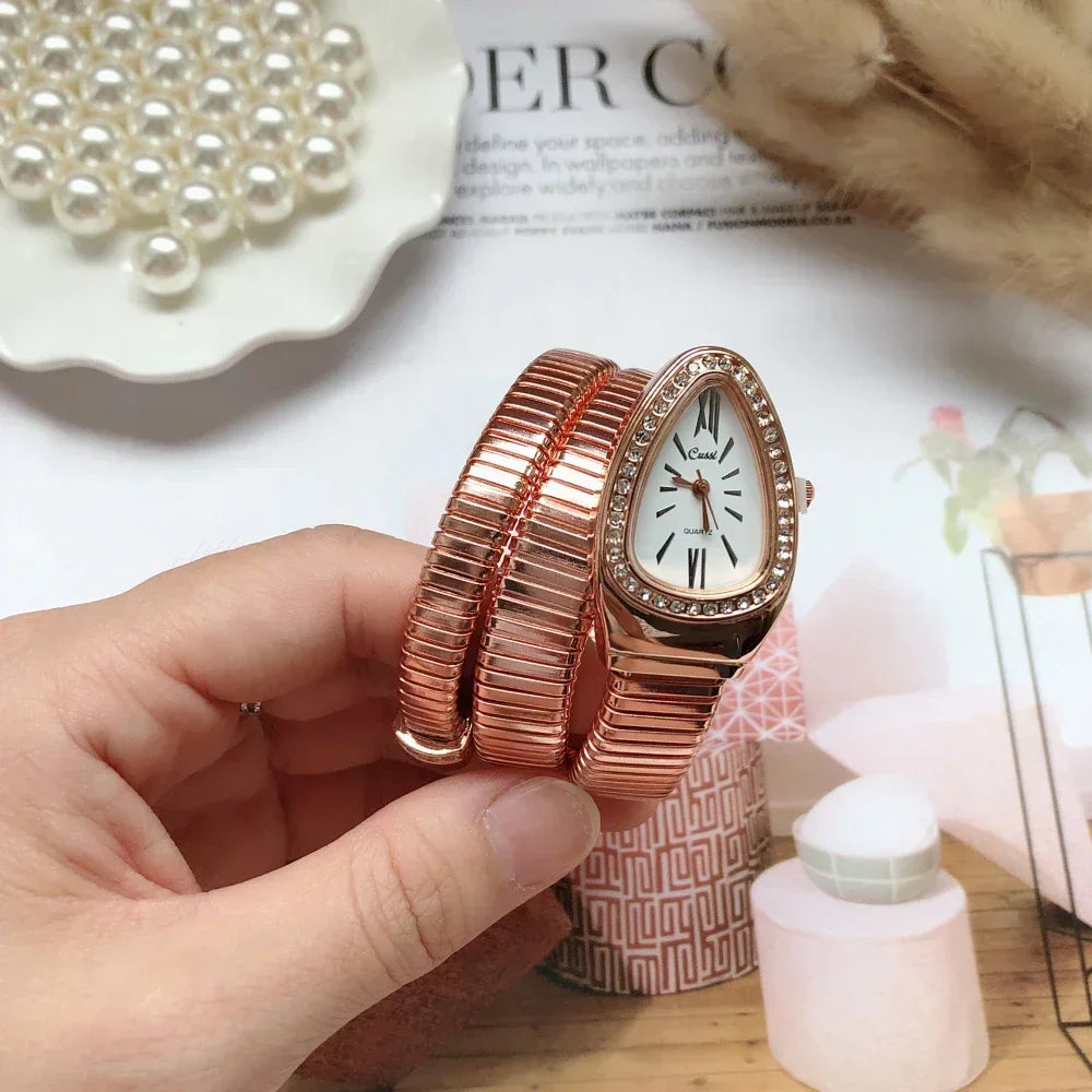 Rose gold bracelet watch held by a hand with a magazine and pearls in the background