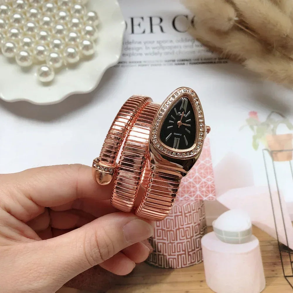 Rose gold watch held by a hand with a magazine and pearls in the background