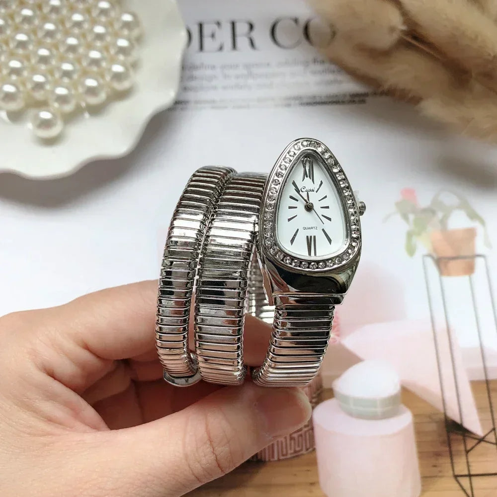 Silver watch with bracelet held by a hand on a blurred background