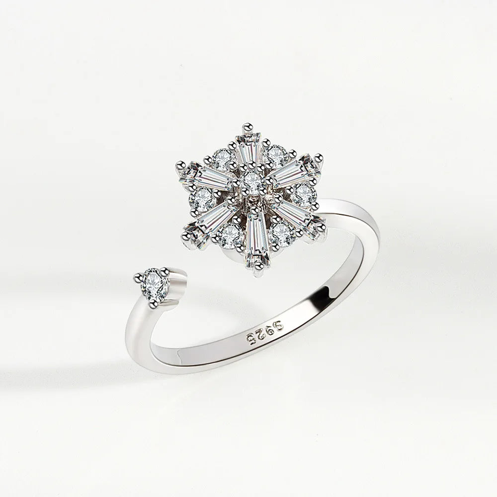 Silver ring with diamond flower design on a white background