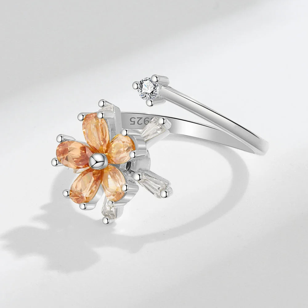 Silver ring with orange gemstones on a light gray background
