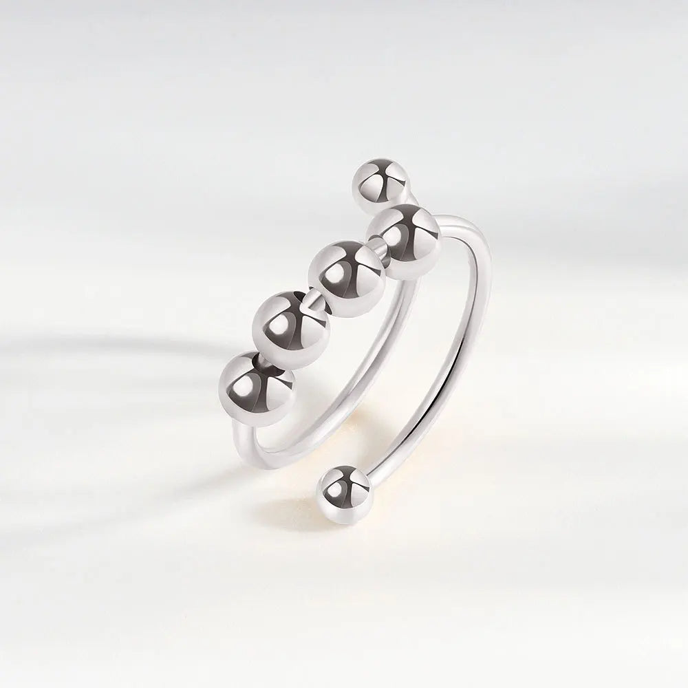 Silver ring with spherical beads on a light gray background