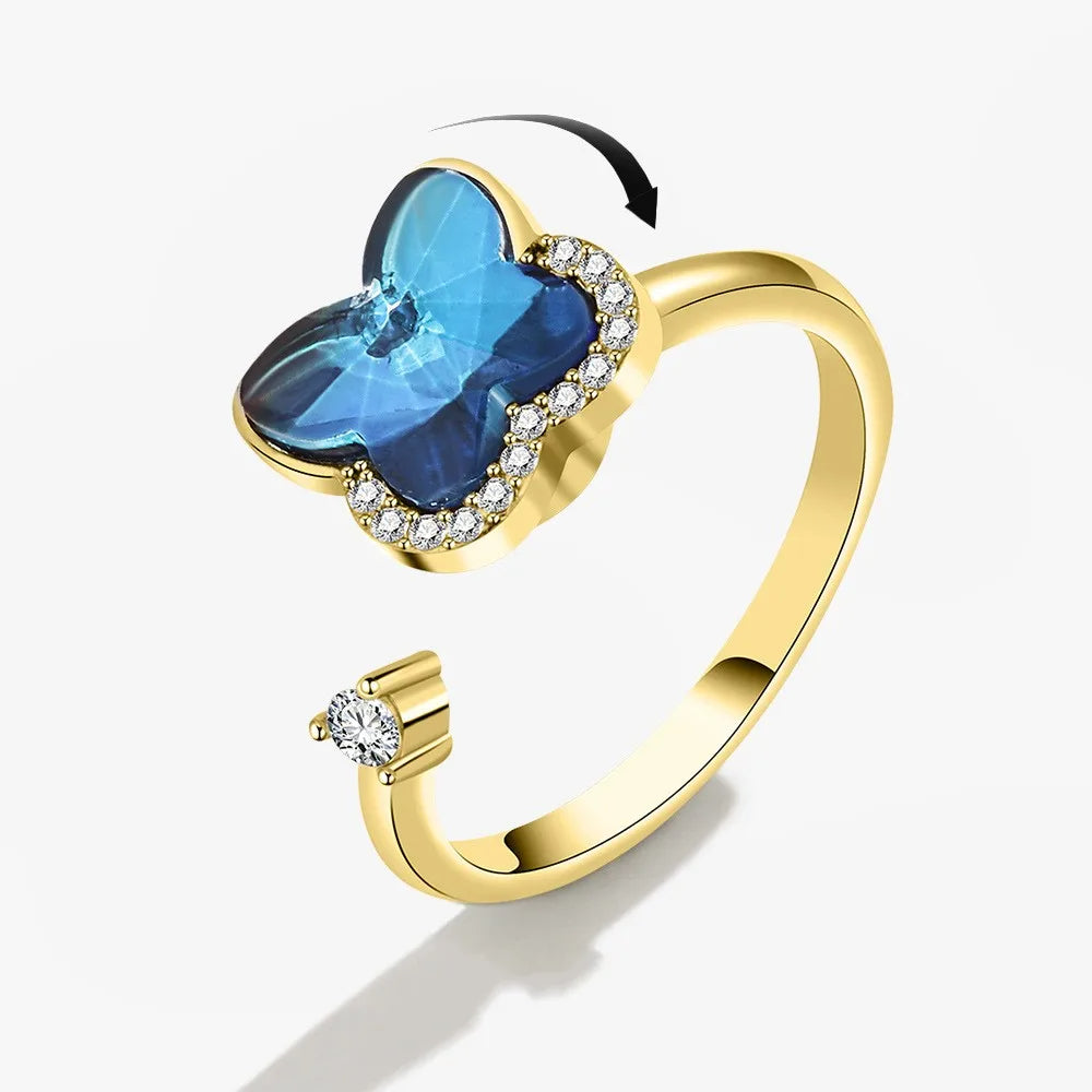 Gold ring with a blue gemstone butterfly design on a white background