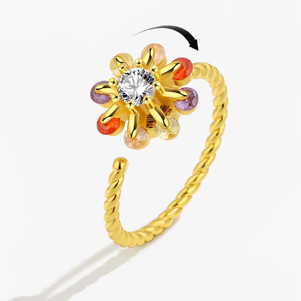 Gold ring with a central diamond and colorful gemstones on a white background