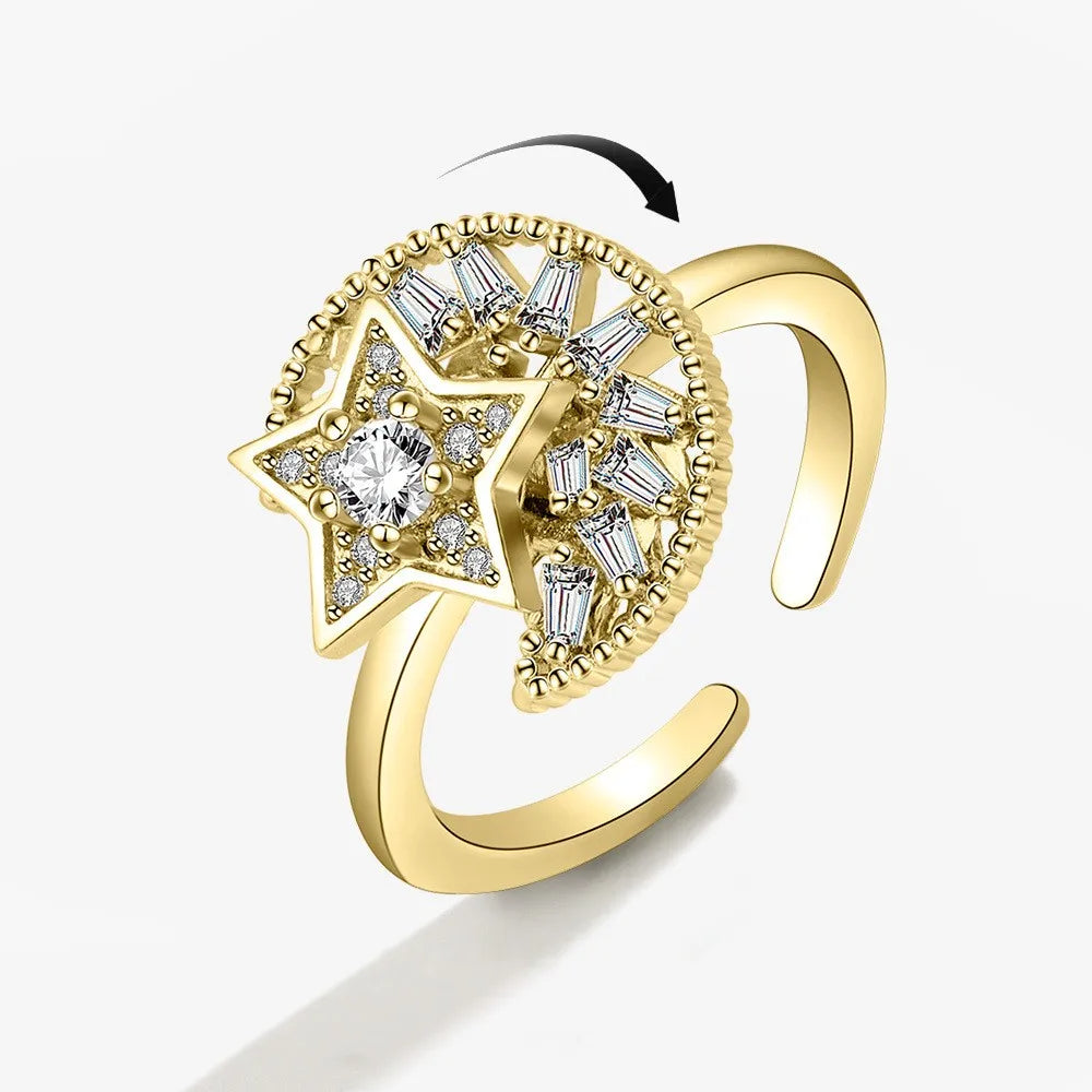 Gold ring with star and moon rotating design on a white background