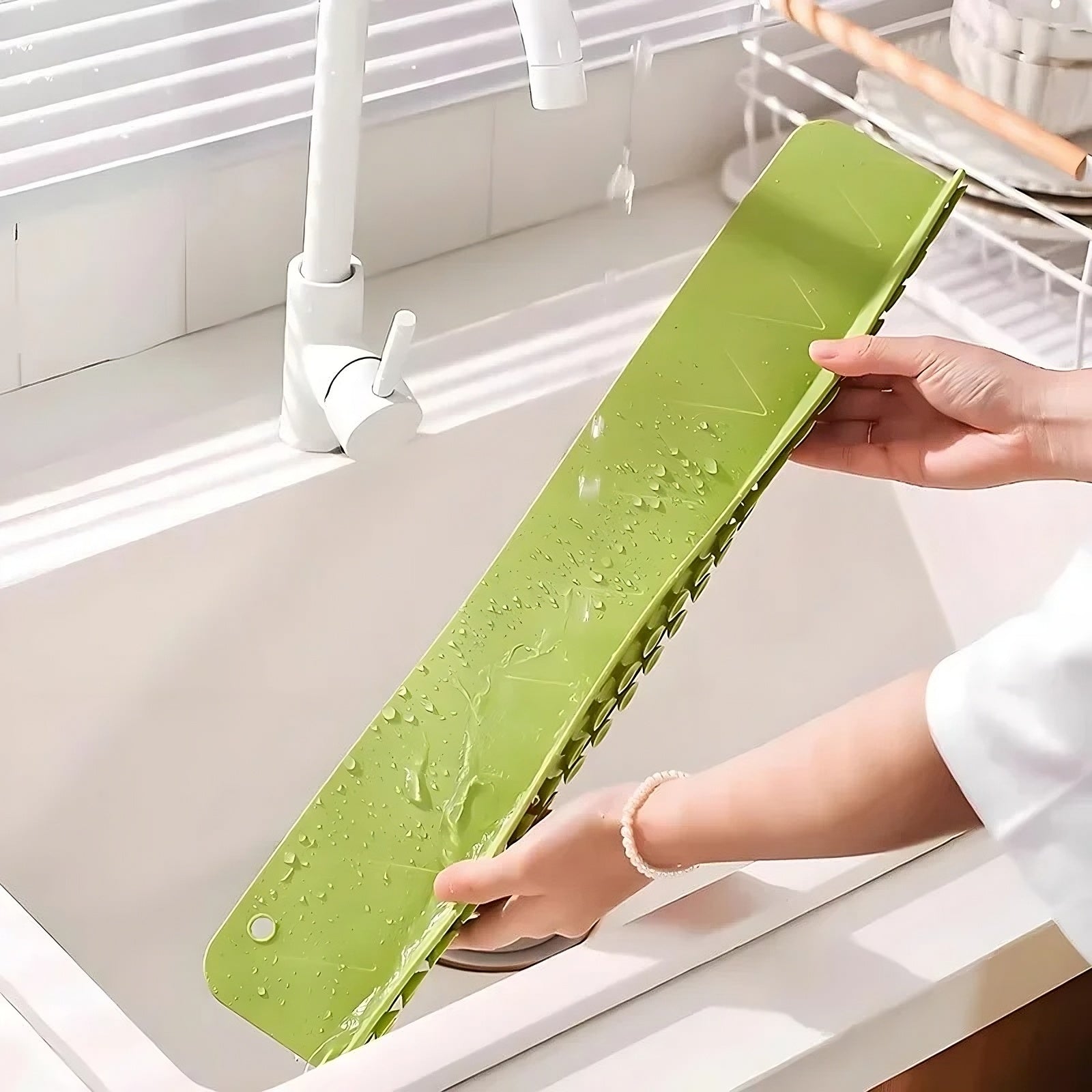 Green sink splash guard with water droplets held over a sink