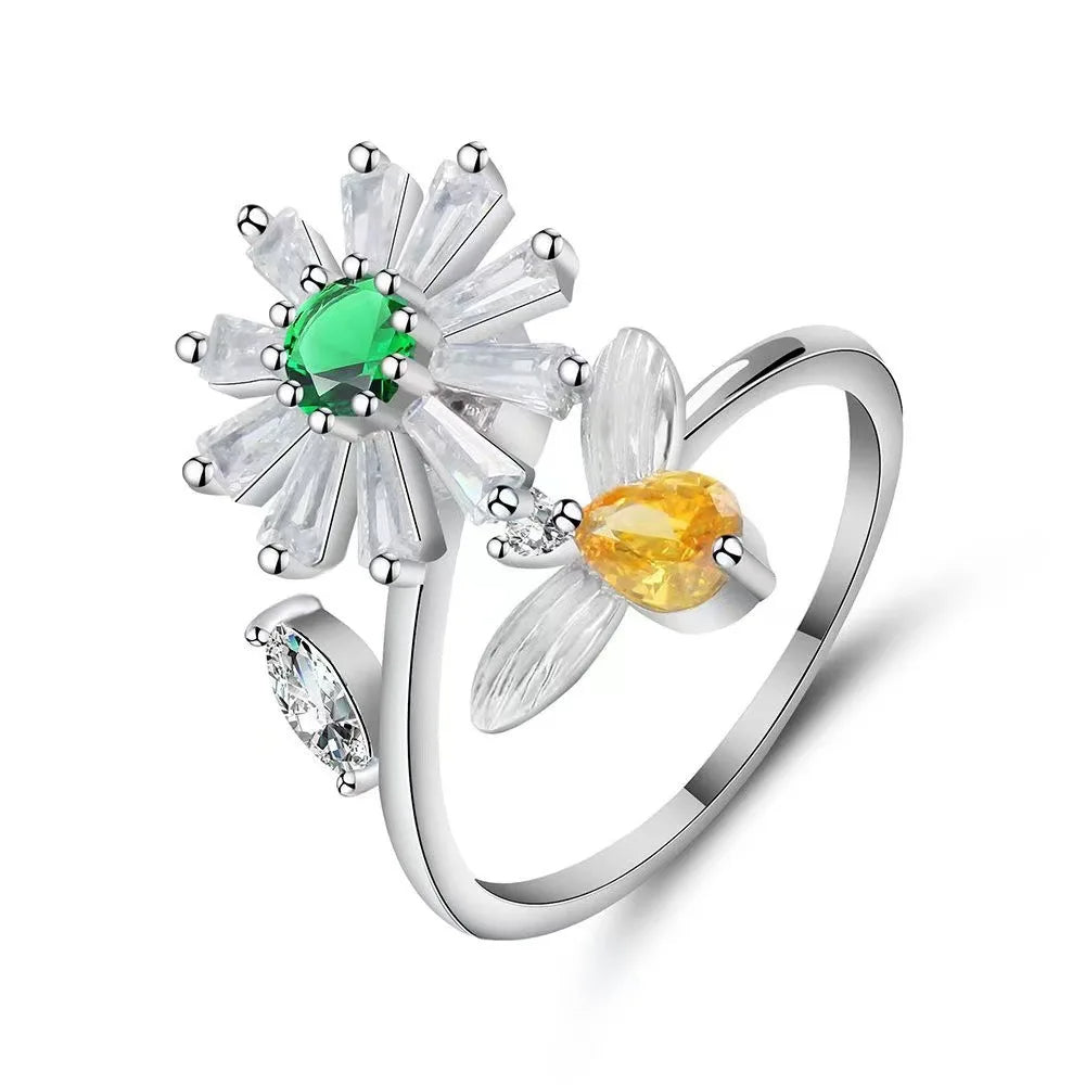 Silver ring with floral design and gemstones on a white background
