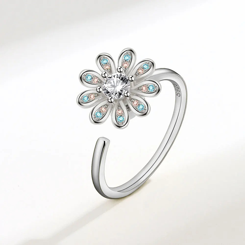 Silver ring with a flower design and colorful gemstones on a white background
